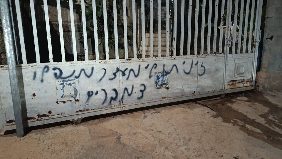 مستوطنون يهاجمون منزلا في دير نظام ويحرقون مركبة ويخطون شعارات عنصرية